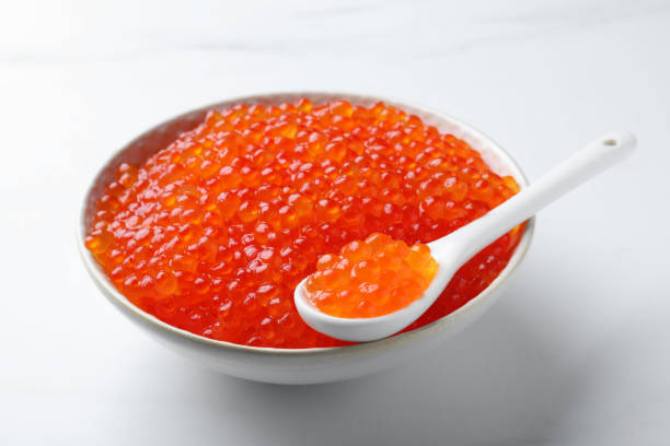 istock Bowl and spoon with delicious red caviar on white table 1438694023