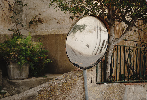 A traffic mirror reflects part of a street of a small Italian village.