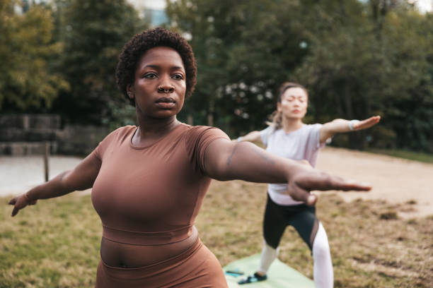 istock Two women practicing yoga and warrior 2 in a public park 1438700902