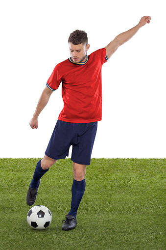 Professional soccer player with red Spain national team jersey about to score a goal with an expression of challenge and decision on his face on white background.