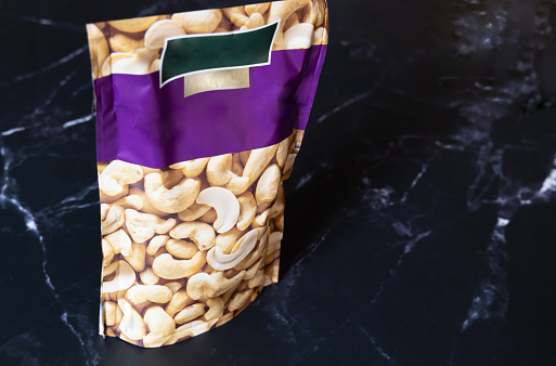 Organic cashew nuts in a package on a dark background.