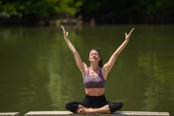 A young woman practicing yoga outdoors at the river