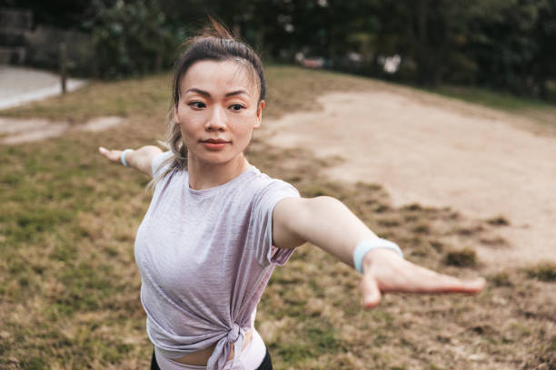 istock One women practicing yoga and warrior 2 in a public park 1438706461