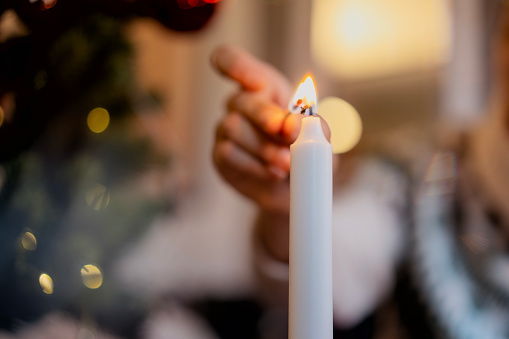 Primer plano de la mano de una mujer encendiendo una vela con fósforos. Vacaciones de Navidad photo