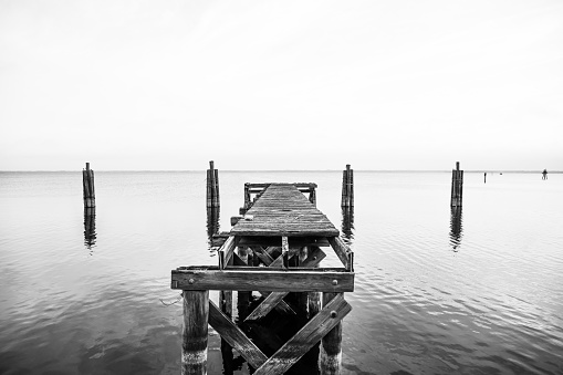 Black and white long exposure picture of torn down dock in water