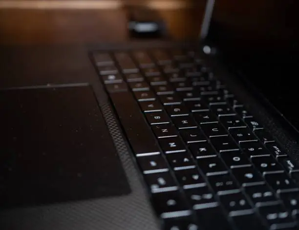 A selective focus on a black laptop keyboard, and a turned-off screen - a concept of modern technology used as a way of working and communication