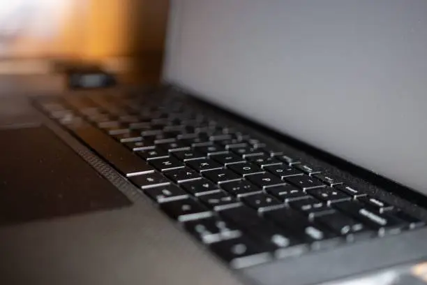 A selective focus on a black laptop keyboard, and a turned-off screen - a concept of modern technology used as a way of working and communication