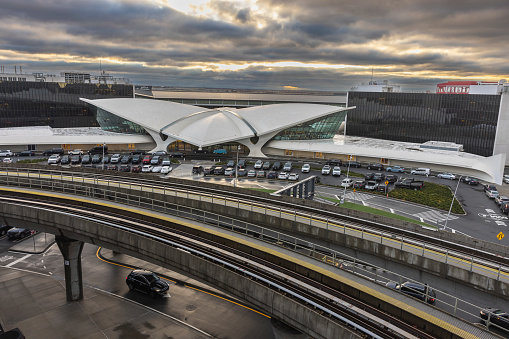 New York City, USA - April 8, 2022: JFK International Airport, one of the busiest in the world, is active even in stormy weather in early morning. Terminal 5 with stuffed parking lot and airtrain tracks at the front.