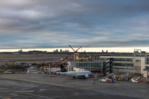 New York City, USA - April 8, 2022: JFK International Airport, one of the busiest in the world, is active even in stormy weather in early morning. Star Alliance airplane parked to the HNB telescopic gangway in Terminal 4.