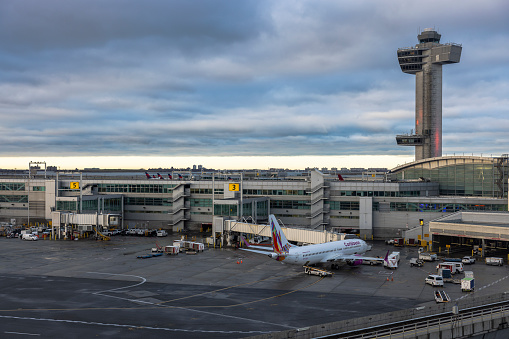 JFK airport in New York during sunset with control tower and parked airplanes