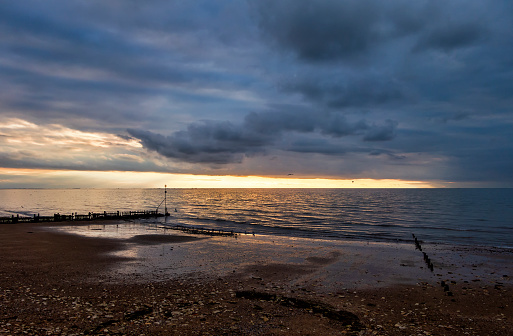 The beach at Hunstanton on the West coast of Norfolk, Eastern England, at sunset with a storm brewing on the horizon, where Lincolnshire is just visible across The Wash.