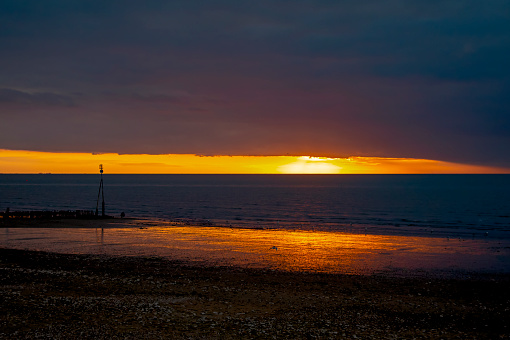 The beach at Hunstanton on the West coast of Norfolk, Eastern England, at sunset. Across The Wash, Lincolnshire is just visible on the horizon.