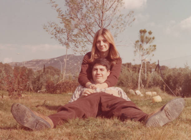 Image taken in the 70s: Smiling young couple lying on the grass looking at the camera stock photo