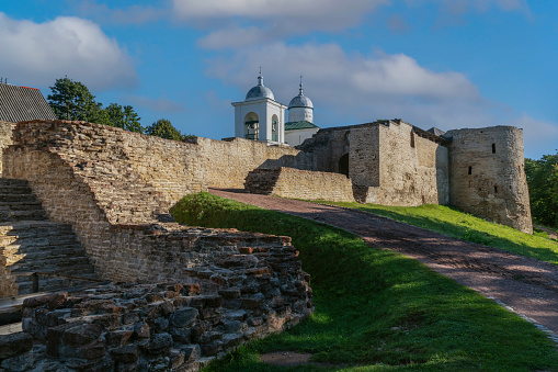 View of the wall of the Izborsk fortress, the Nikolsky Gate and St. Nicholas (Nikolsky) Cathedral (XIV-XVII century) on a sunny summer day, Izborsk, Pskov region, Russia