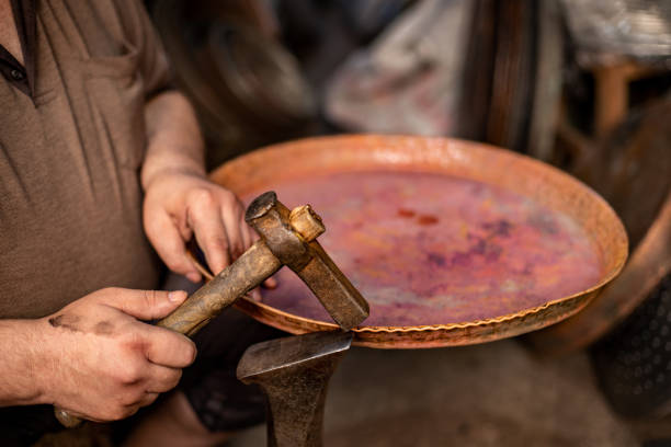 Coppersmith manually forging the copper metal.