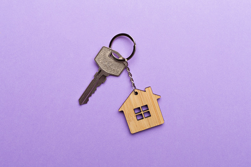 Keys with house-shaped keychain on color background.