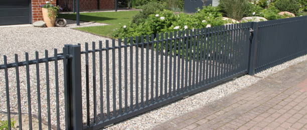 a driveway with a gray sliding gate stock photo