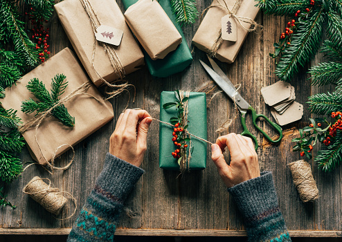 Top view woman's hands wrap artisanal gifts for Christmas.