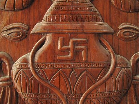A closeup shot of a swastika sculpted on a wooden surface