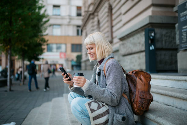 Happy female student using a smart phone outdoors stock photo