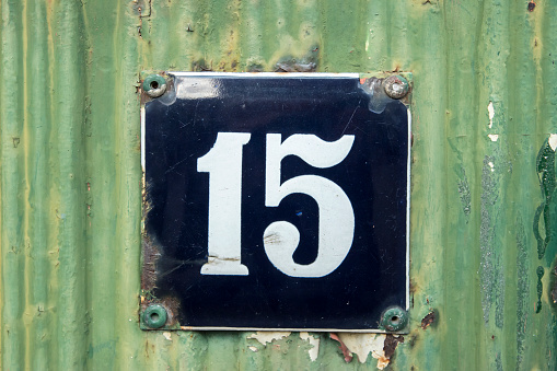 Weathered grunge square metal enameled plate of number of street address with number 15