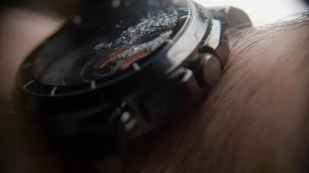 Photo of Extreme close-up of blurry looking wristwatch with water particles, wearing on the arm, background concept