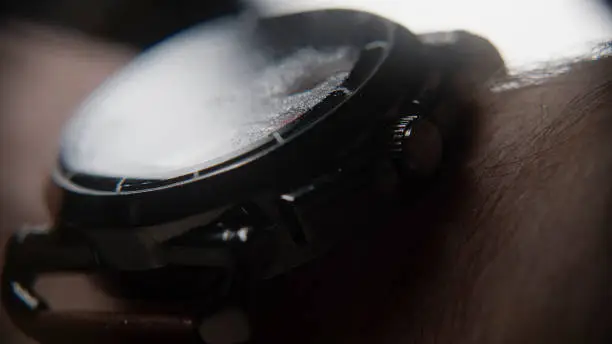 Photo of Extreme close-up of blurry looking wristwatch with water particles, wearing on the arm, background concept