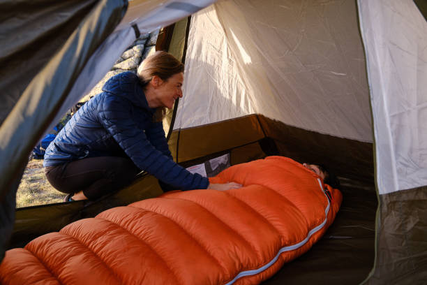 Mother waking son in tent in the morning stock photo