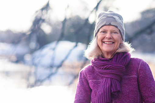 Portrait of a happy woman in her late sixties outdoors in nature in winter.