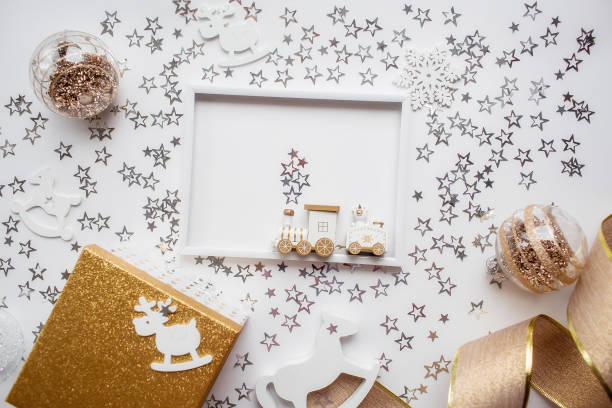 istock Christmas frame with white and gold decorations, gift box and train on a white background. Flat layout, top view, place to copy. The concept of the new year 2023 1438728532