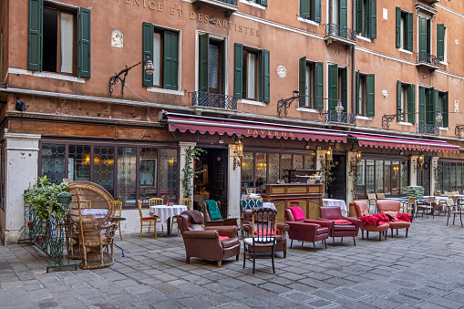 Venice, Italy - October 6th 2022:  Tables and chairs from at outdoor sidewalk restaurant on a small square in the center of the old and famous Italian city Venice