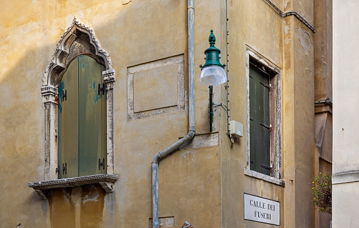 Venice, Italy - October 6th 2022:  Streetcorner with streetlamp and window with shutters in a narrow street in the center of the old and famous Italian city Venice