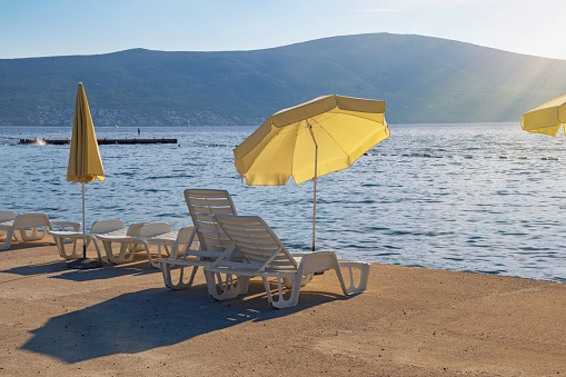 Beautiful Mediterranean landscape, autumn beach vacation.  Beach umbrellas on coast of Kotor Bay. Montenegro,  Adriatic Sea,  Tivat