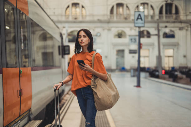 młoda, piękna hiszpanka korzysta z telefonu komórkowego na stacji kolejowej, czekając na wejście do wagonu kolejowego - hiszpanka_& zdjęcia i obrazy z banku zdjęć