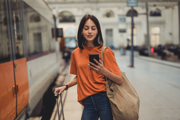istock A young beautiful Spanish woman is using a mobile phone at a train station while waiting to enter a train car 1438741689
