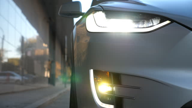 Close up of headlights of modern car. Switching of automobile LED head lights. New auto headlamp. Front of vehicle with flashing lamp. Detail view
