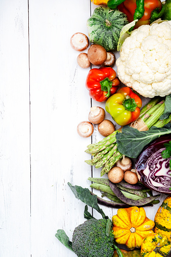 Autumn seasonal food, vegetarian cooking ingredients. Organic vegetables, pumpkin, mushrooms, asparagus, paprika, legumes, chickpeas and olive oil on rustic wooden table, copy space. Thanksgiving dinner preparation