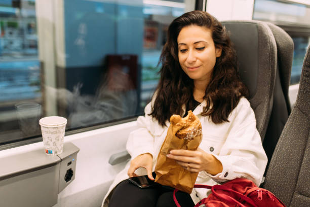 istock Woman checking emails and holding croissant on the train 1438742487