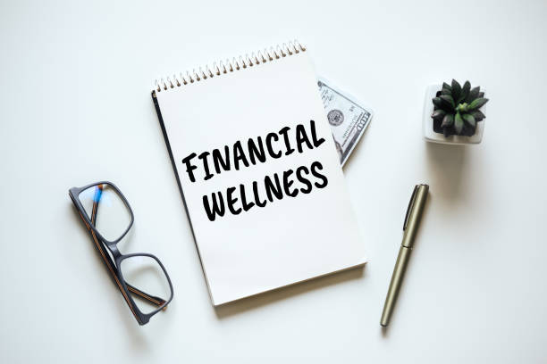 istock Financial Wellness. Black frame with word Financial Wellness on table with mason jar saving bank, stationery and glasses. Investment in life insurance and healthcare concept 1438742765