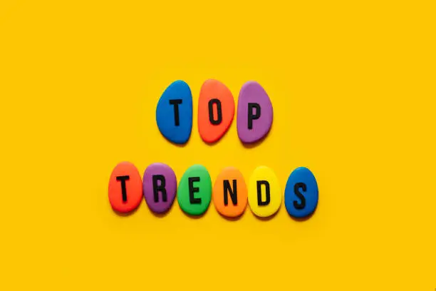 Photo of Top trend, forecasting, process of researching and formulating predictions on consumers future buying habits, Whats new in business. Text Top trends from color blocks on yellow background.