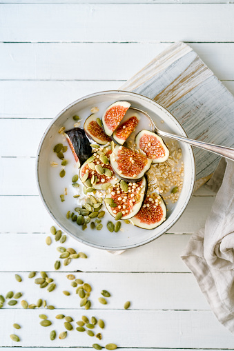 Sliced figs, oats and quinoa with pumpkin seeds and a coconut drink in a bowl