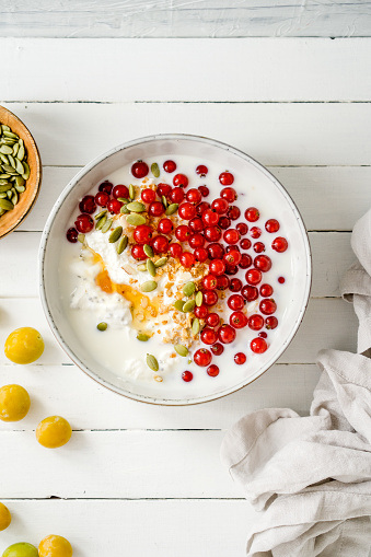 Red currants, granola and pumpkin seeds together with curd cheese in a bowl