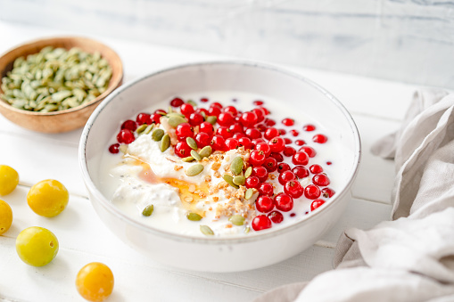 Red currants, granola and pumpkin seeds together with curd cheese in a bowl
