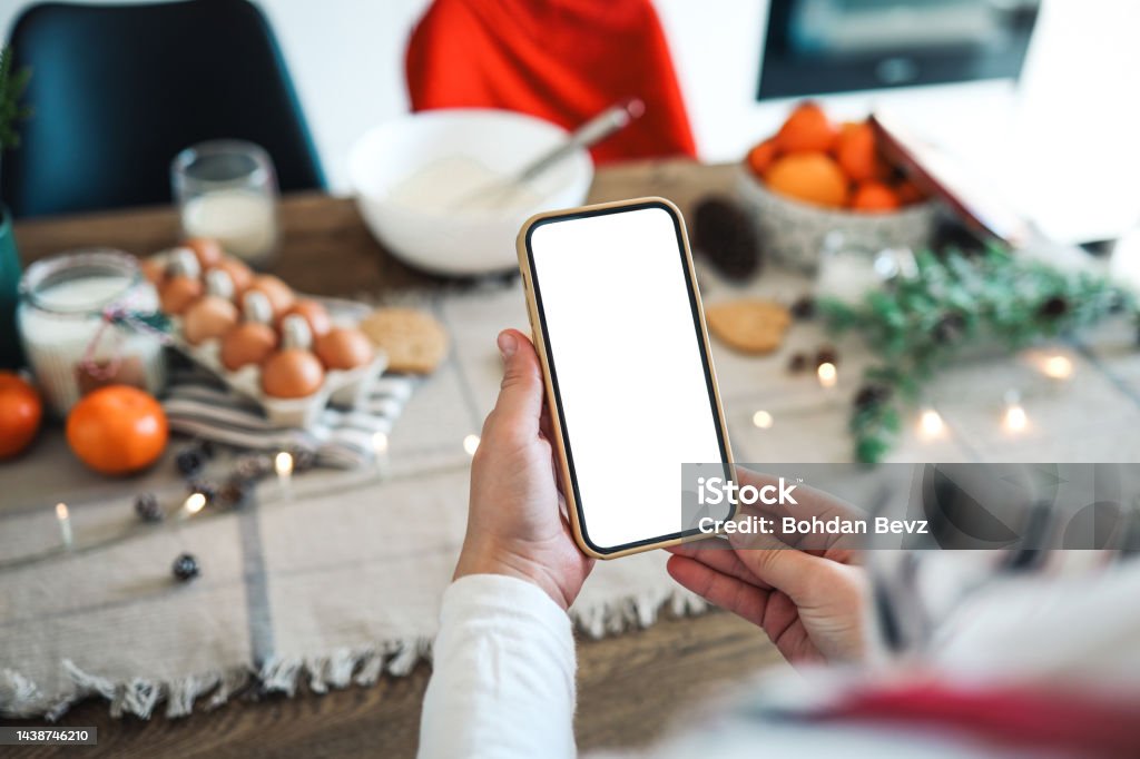 Phone with a blank screen in the hands on the background of Christmas cooking. Place for text. Master class invitation. Merry Christmas Christmas Stock Photo