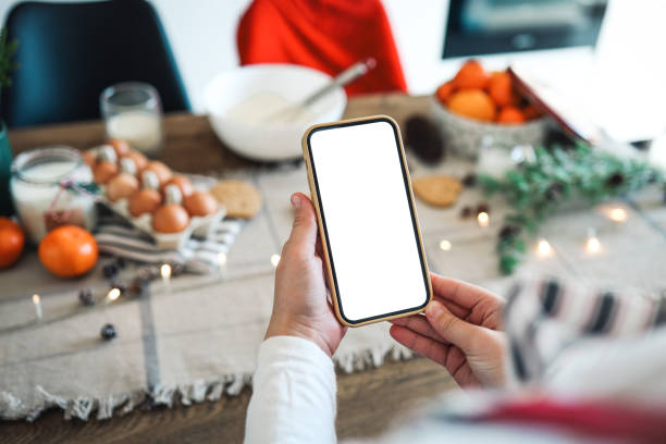 phone with a blank screen in the hands on the background of christmas cooking. place for text. master class invitation. merry christmas - egg cell imagens e fotografias de stock