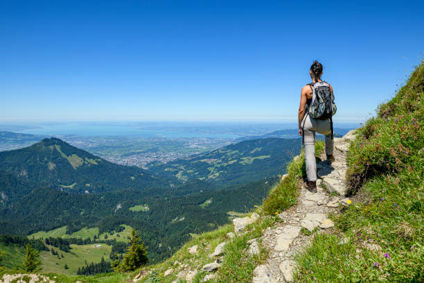 Young woman resting in the mountains (Moerzelspitze) looking at Lake of Constance in the background