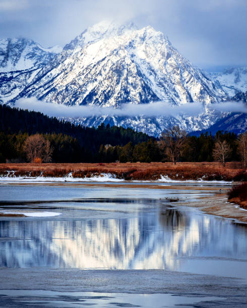 uma montanha nevada refletindo em um lago gelado - nature reflection grand teton teton range - fotografias e filmes do acervo