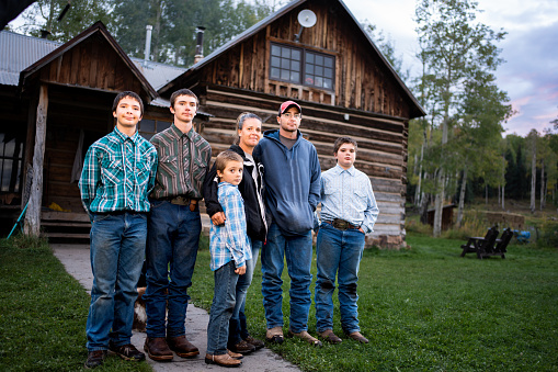Young Family of Six, Mother, Father and Four Boys Posing Portrait In front of an old Log Cabin Home in Southwest Colorado Rocky Mountains Near Telluride