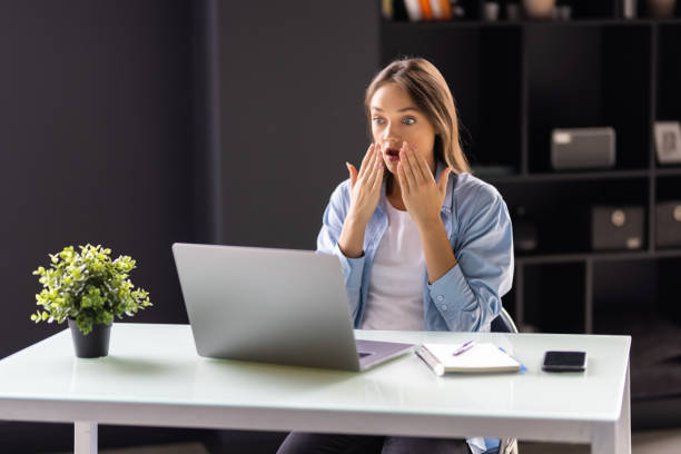 istock Surprised young businesswoman using her laptop at office 1438751412