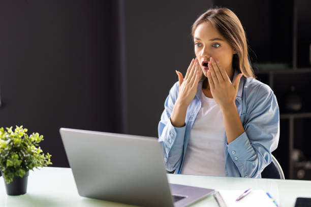 istock Surprised young businesswoman using her laptop at office 1438752874
